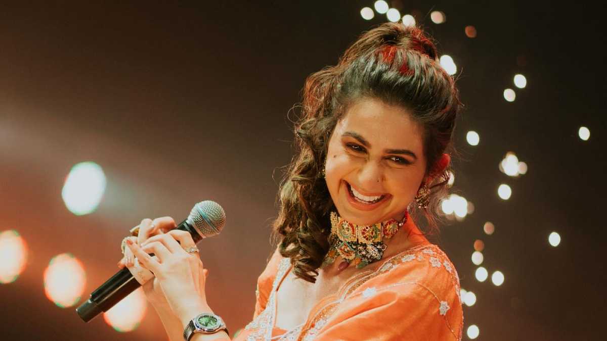 Kinjal Dave performing live on stage during a Navratri Garba night, a large crowd dancing in traditional outfits.